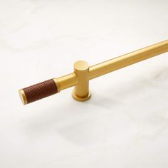 a close up of a metal pole on a white surface with a gold colored handle