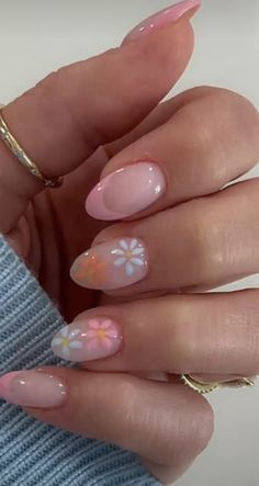 a woman's hand with pink and white flowers on it, holding her nails