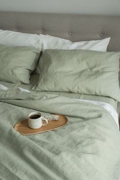 a tray with a cup of coffee sitting on top of a bed next to pillows