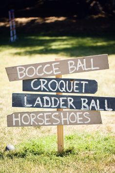 a wooden sign sitting on top of a grass covered field next to a horse shoe