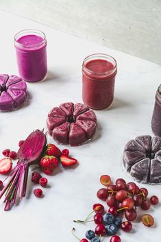 various fruits and vegetables are arranged on a table with some juices in the background