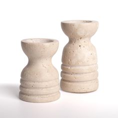 two white vases sitting next to each other on a white surface with no one around them