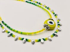 This dainty and whimsical gradient evil eye necklace is both sophisticated and understated. The handmade yellow and white evil eye is crowned with two pewter beads. I used Japanese seed beads in sunny bright yellow, acid green, meadow green and forest green, silver and translucent white to build the gradient colors enhancing the handmade bead. Silver gekko glass beads with their triangular shape add just the right amount of sparkle and edge to this design. Evil eye is believed to protect its own Green Chartreuse, Handmade Evil Eye, Evil Eye Necklace, Handmade Beads, Eye Necklace, Dainty Necklace, Metallic Accents, Gradient Color, Chain Styles