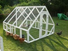 a chicken coop with chickens in it on the grass