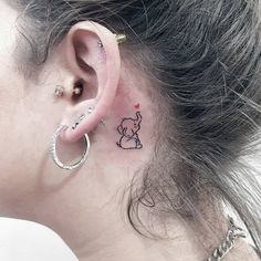 a woman's ear has a small elephant tattoo on it