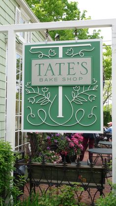 a sign for tate's bake shop in front of a building with potted plants