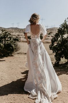 a woman in a white dress is flying a butterfly above her head and looking off into the distance