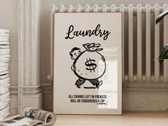 a poster with the words laundry on it next to a stack of newspapers and a potted plant