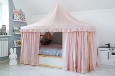 a pink tent bed with curtains on the top