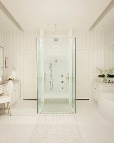 a white bathroom with a walk in shower next to a bathtub and vanity area