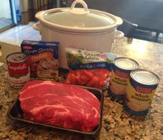 raw meat, potatoes, carrots and other ingredients are on the counter next to an open crock pot