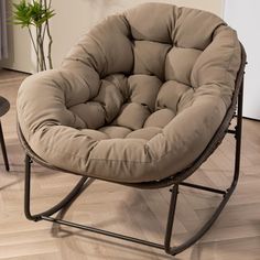 a brown chair sitting on top of a hard wood floor next to a potted plant