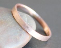 a pink gold wedding ring sitting on top of a rock