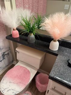 a pink toilet in a bathroom next to a sink and mirror with plants on it