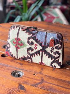 a small purse sitting on top of a wooden table next to a potted plant