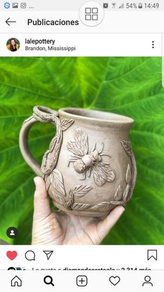 someone is holding up a mug that has been decorated with flowers and leaves on it