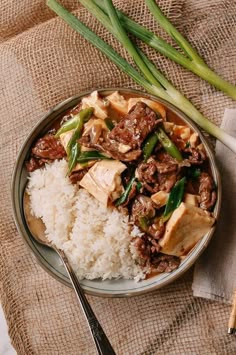 a plate with rice, meat and vegetables on it next to some chopsticks