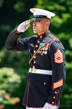 a man in uniform saluting while wearing a hat