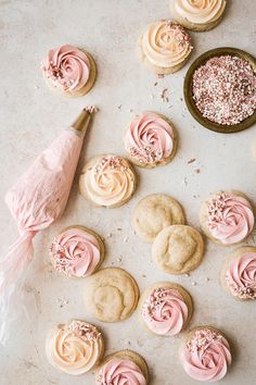 pink frosted cookies and cupcakes on a table