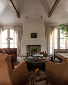 a living room with couches, chairs and a fire place in the middle of it