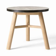 a round wooden table with black top on a white background in the shape of a stool