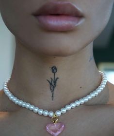 a close up of a person wearing a necklace with a flower and heart on it