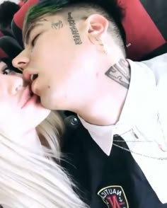 a man and woman kissing each other with tattoos on their foreheads in front of them