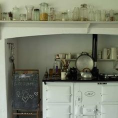 an old fashioned stove in a kitchen with lots of glassware on the top shelf