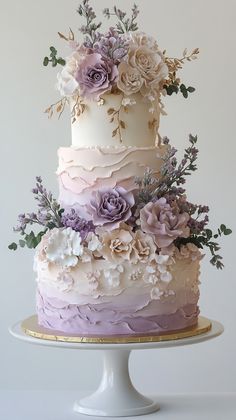 a three tiered cake decorated with flowers and greenery