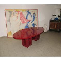 a red table sitting in front of a painting