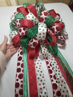 a hand is holding a christmas present wrapped in red, green and white paper with polka dots