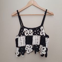 a black and white crocheted top hanging on a wooden hanger