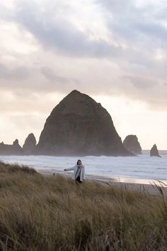 a man standing on top of a sandy beach next to the ocean