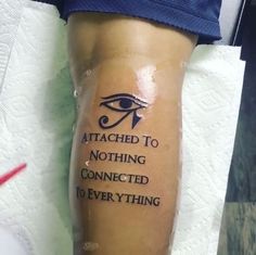 an eye tattoo on someone's leg that says, attached to nothing connected to everything