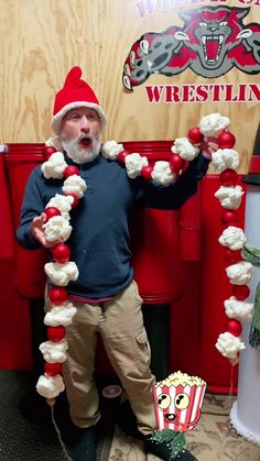 a man wearing a santa hat and holding up some candy canes while standing in front of a wrestling booth