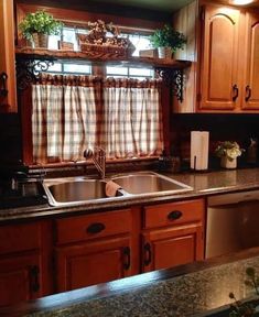 a kitchen with wooden cabinets and stainless steel sink, dishwasher and window in the corner