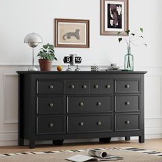 a black dresser in a white room with pictures on the wall