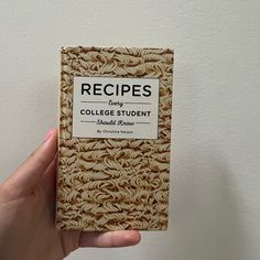 a person holding up a small book with noodles on it's front and back cover