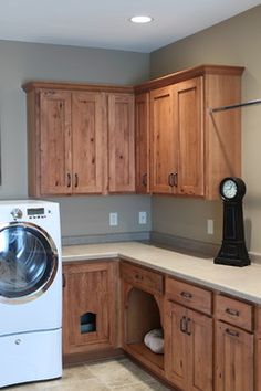 a washer and dryer sitting in a kitchen next to wooden cabinets with a clock on top