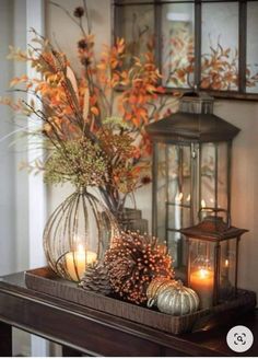 a table topped with a vase filled with lots of flowers next to a lantern and candles