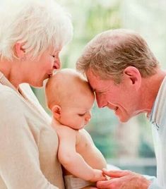 an older man and woman holding a baby