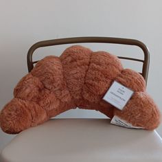 a brown teddy bear sitting on top of a white chair next to a tag that says,