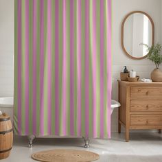 a bathroom with a shower curtain that has stripes on it, and a rug in front of the bathtub