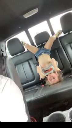 a young child is upside down in the back seat of a car