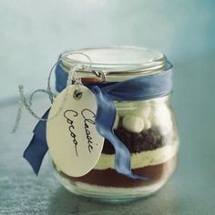 a glass jar filled with cake mix and a blue ribbon around the top that has a tag on it