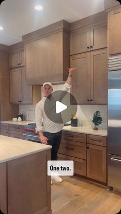 a man is standing in the middle of a kitchen with his hand up to the ceiling