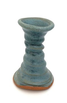 a small blue vase sitting on top of a white table next to a brown base