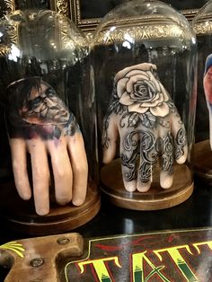 three glass jars with fake hands and tattoos on them