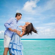 a man and woman standing next to each other near the ocean