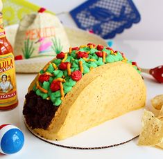 a taco cake is on a plate with chips and condiments around it